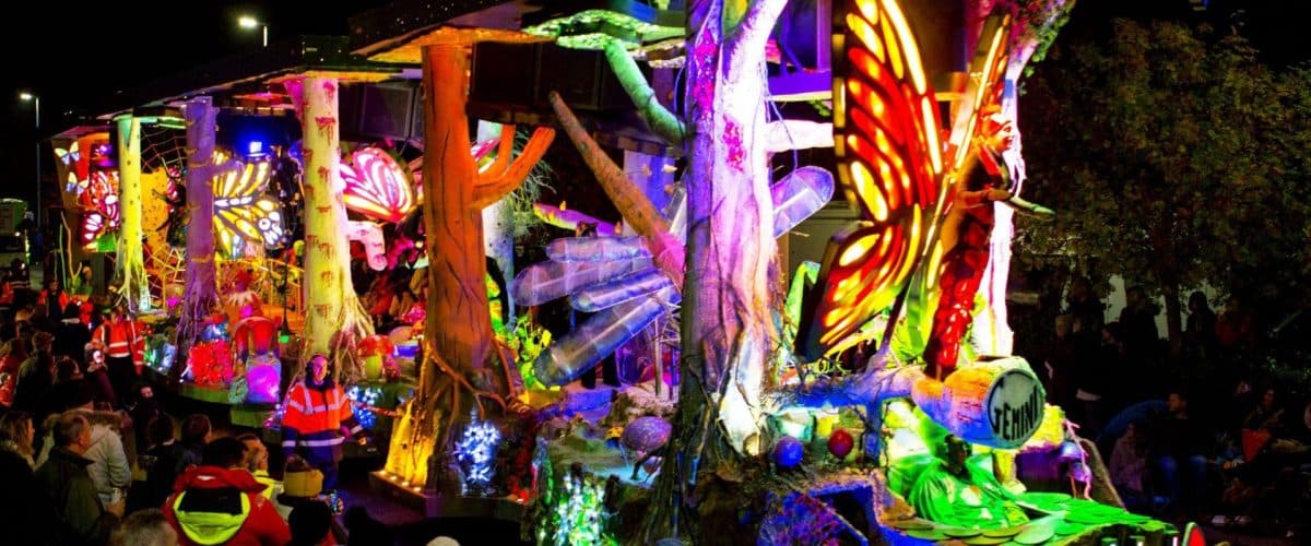 The illuminated Gemini carnival cart passing spectators at night